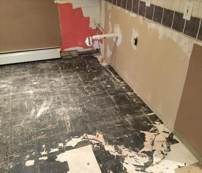 This is a photo of an empty water damaged kitchen after the cabinets and countertops were removed.